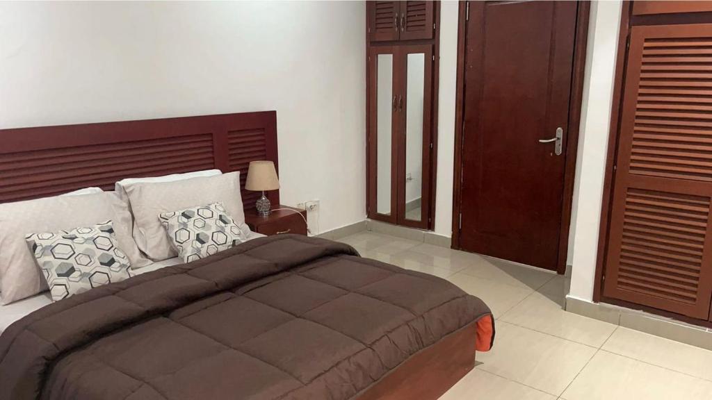 a bedroom with a large bed and a wooden headboard at RESIDENCE ABBAS in Yaoundé