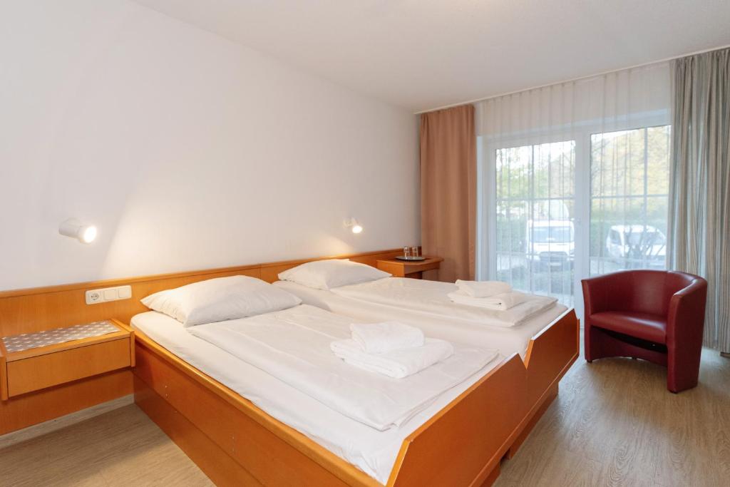 - une chambre avec un grand lit et une chaise rouge dans l'établissement Aschau-Apartments, à Aschau im Chiemgau