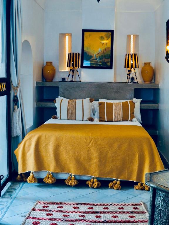 a bedroom with a bed with a yellow bedspread and two lamps at Riad El Youssoufi in Marrakesh