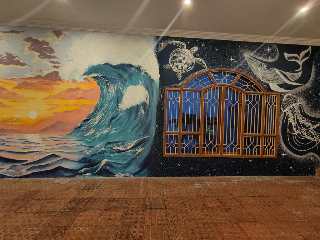a wall with a painting of a wave and a window at Unpack Hostel in Puducherry