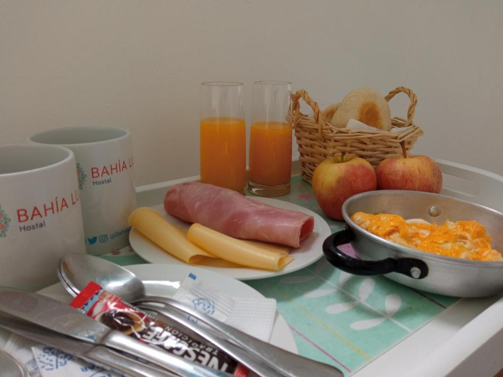 una barra de cocina con un desayuno de huevos salchichas y fruta en Bahía Luz Hostal en Concón