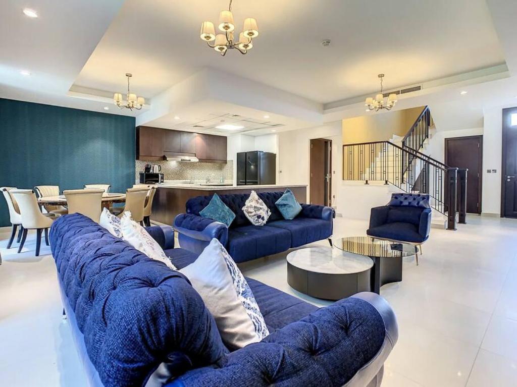 a large living room with blue couches and a kitchen at Key View - Villa, Casa Flores in Dubai