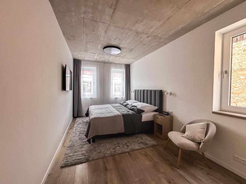 a bedroom with a bed and a chair at CASTLE apartments - City Center in Spišské Podhradie