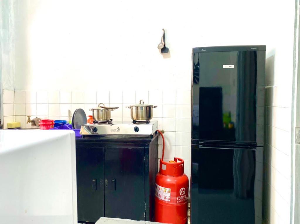 eine Küche mit einem Kühlschrank und einem Herd mit Töpfen darauf in der Unterkunft Drew Apartment Tanga in Tanga
