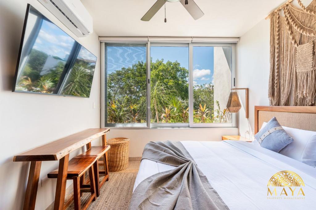 トゥルムにあるNHOA 307B Lux 1BR Condo Pool View in Aldea Zamaのベッドと大きな窓のある寝室