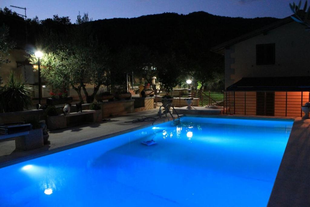 un hombre está jugando en una piscina azul por la noche en Casale degli ulivi, en Arezzo