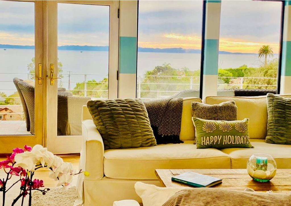 a living room with a yellow couch and large windows at Summer Beach House in Summerland