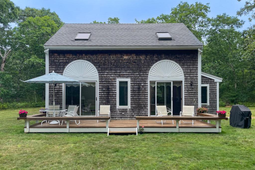 a house with a deck with chairs and an umbrella at Vineyard Vacation Cottage in Chilmark