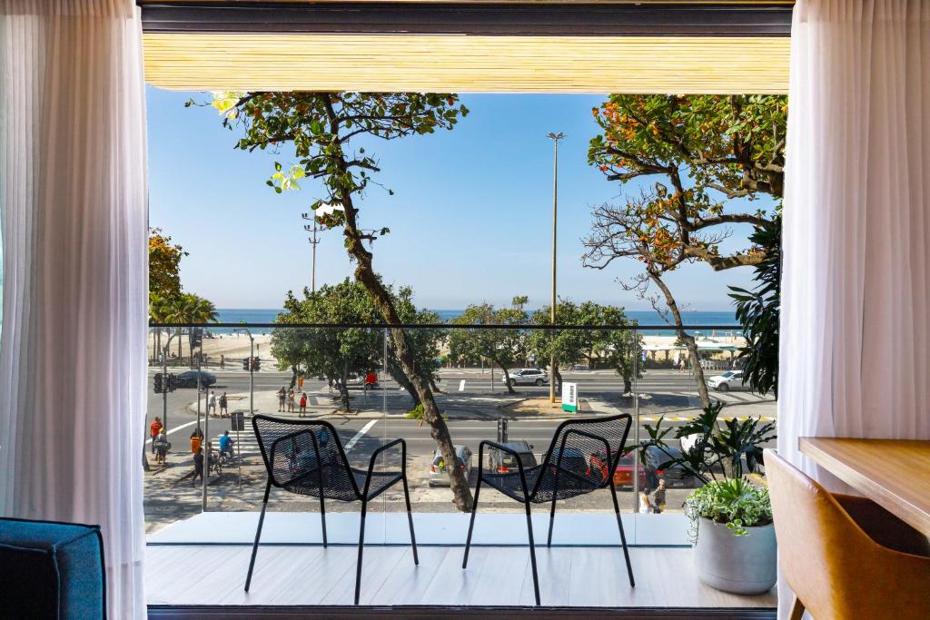 a balcony with chairs and a view of a parking lot at Unhotel - Luxuoso Loft com Vista Mar na Praia de Copacabana in Rio de Janeiro