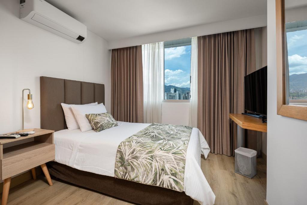 um quarto de hotel com uma cama, uma secretária e uma janela em Affinity Aparta Hotel em Medellín
