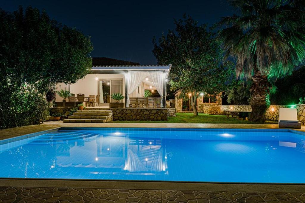 a swimming pool in front of a house at night at Eleonas Villa in Fiolítis