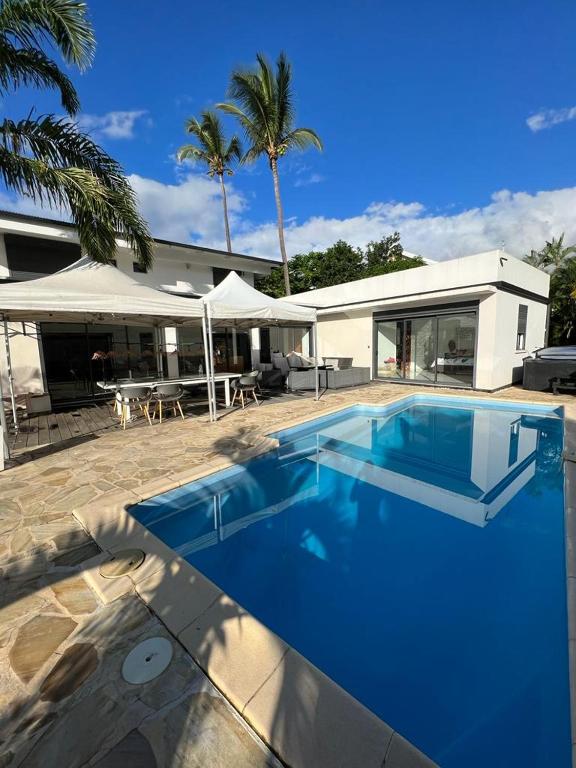 uma grande piscina azul em frente a uma casa em Villa Grande Montagne em La Possession