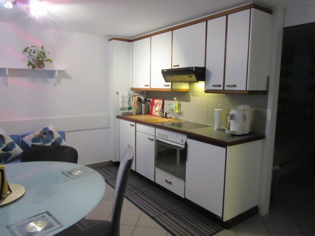 una cocina con armarios blancos y una mesa en una habitación en Casa Rosa, en Biasca
