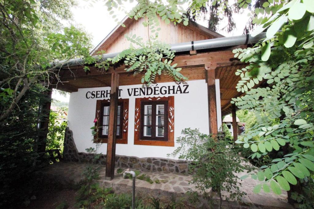 una pequeña casa con un cartel delante en Cserhát Guesthouse en Felsőtold