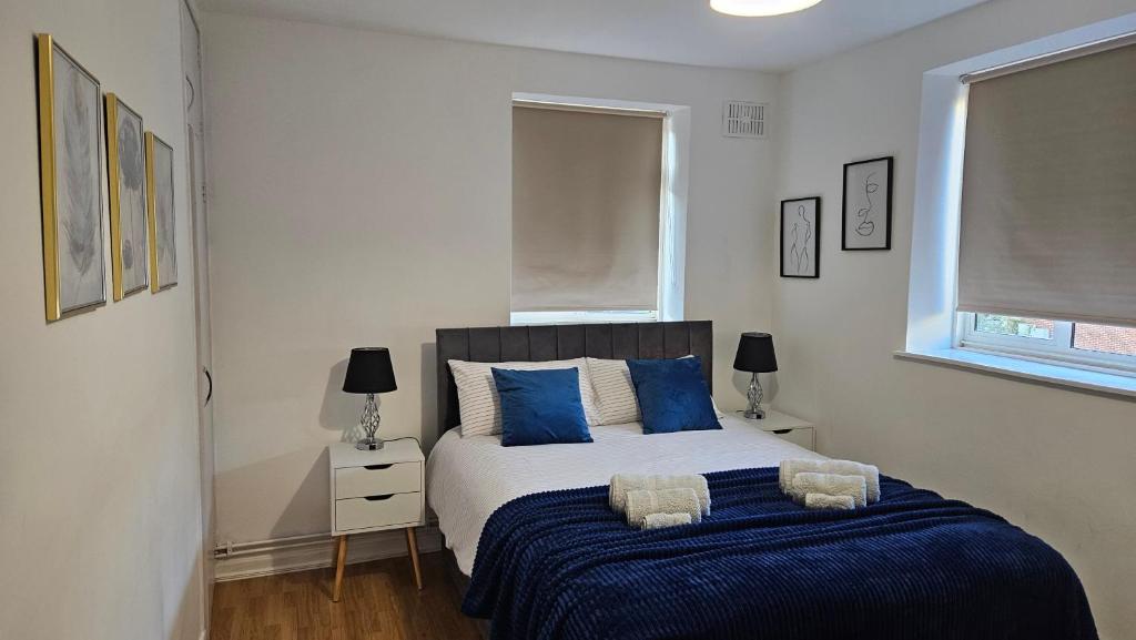 a bedroom with a large bed with blue pillows at Chic Two Bedroom Apartment in the Heart of Battersea Modern and Comfy in London