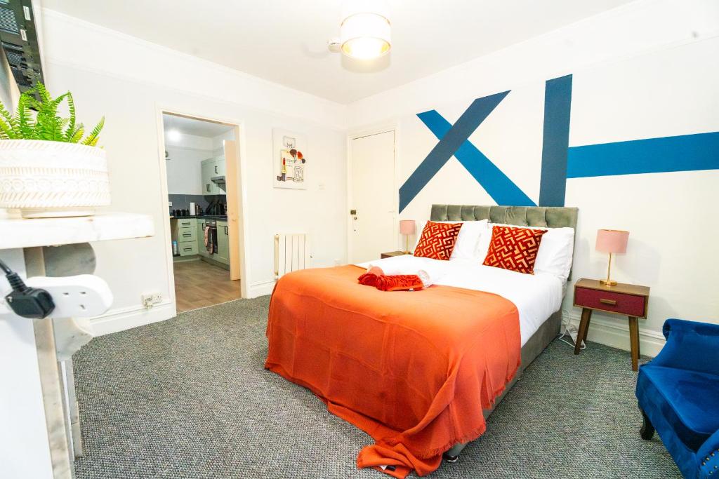 a bedroom with a bed with an orange blanket at Bright Medway studio flat opposite Chatham station in Chatham
