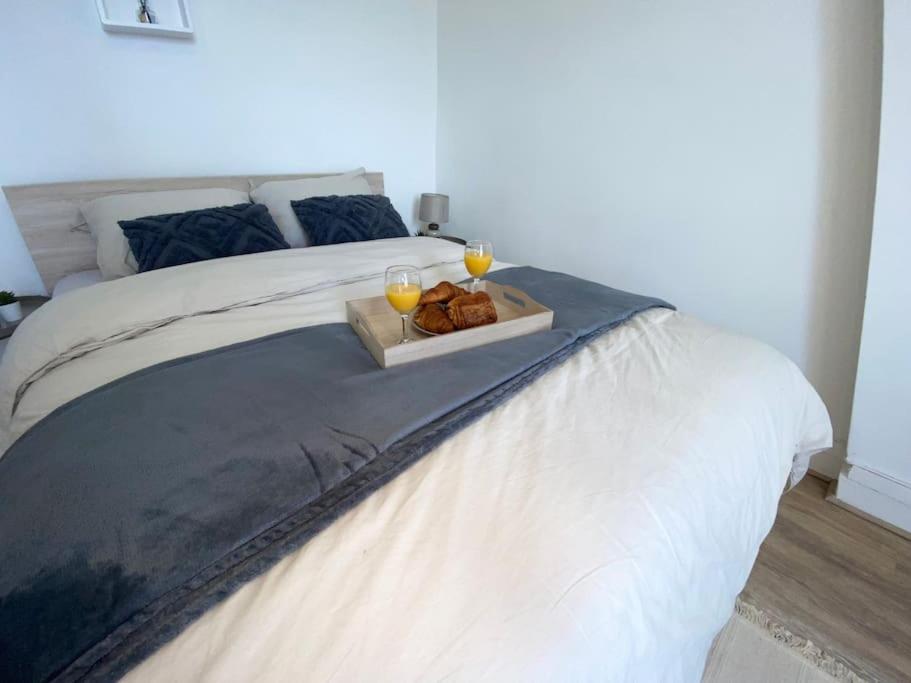 Bett mit zwei Gläsern Wein und einem Tablett mit Essen in der Unterkunft Petit Cosy Aux Portes de Paris, En Face Du M 13 in Asnières-sur-Seine