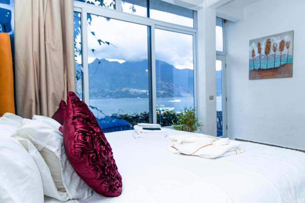 Un dormitorio con una cama con almohadas rojas y una ventana en TIBERIAS by luxury Atitlan, en San Pedro La Laguna