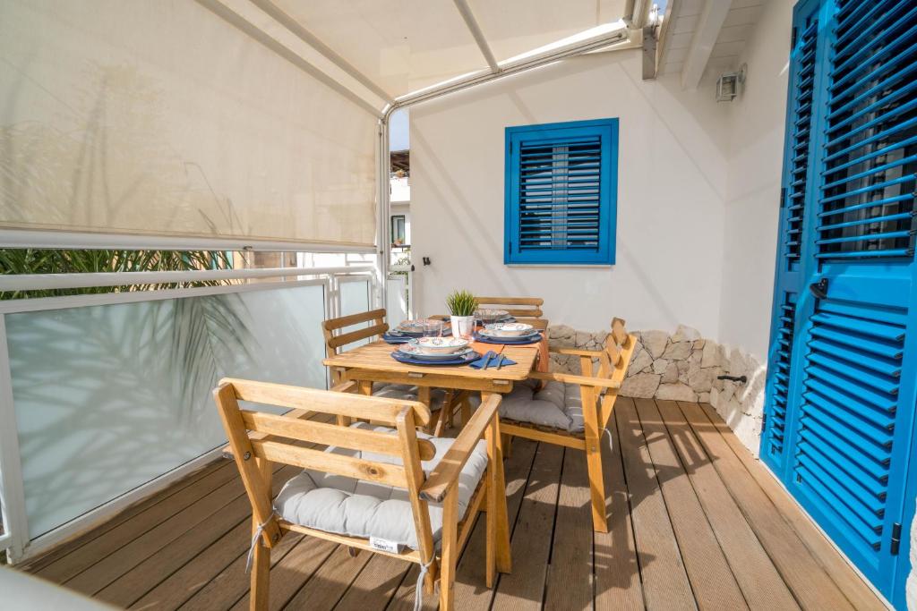 une table et des chaises en bois sur une terrasse avec une fenêtre dans l'établissement CapoSud - Appartamento Sottovento, à Marina di Ragusa