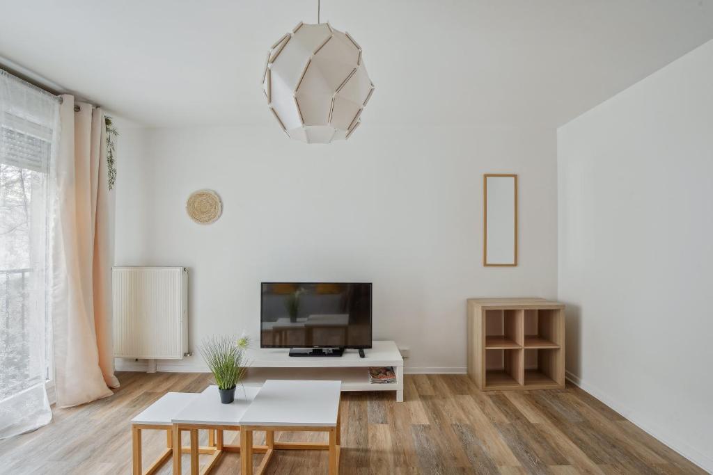 sala de estar con TV y mesa en Chic and spacious apartment with balcony, en Ivry-sur-Seine