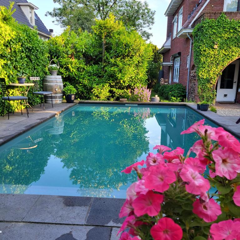 a swimming pool with pink flowers in front of a house at Appartement Klein Waldeck in Velp