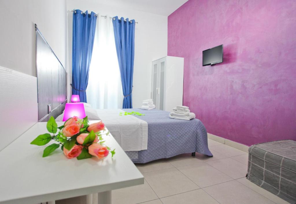 a pink room with a bed with flowers on a table at B&B Napolì 2 in Naples
