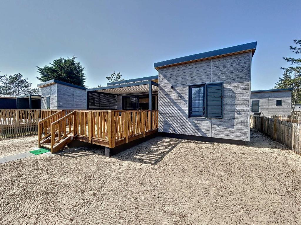 une petite maison avec une clôture en bois dans une cour dans l'établissement Chalet cosy 4 pers - Piscine chauffée - Proche plage et commerces - Terrasse et jardin privés - FR-1-361-504, à Jullouville