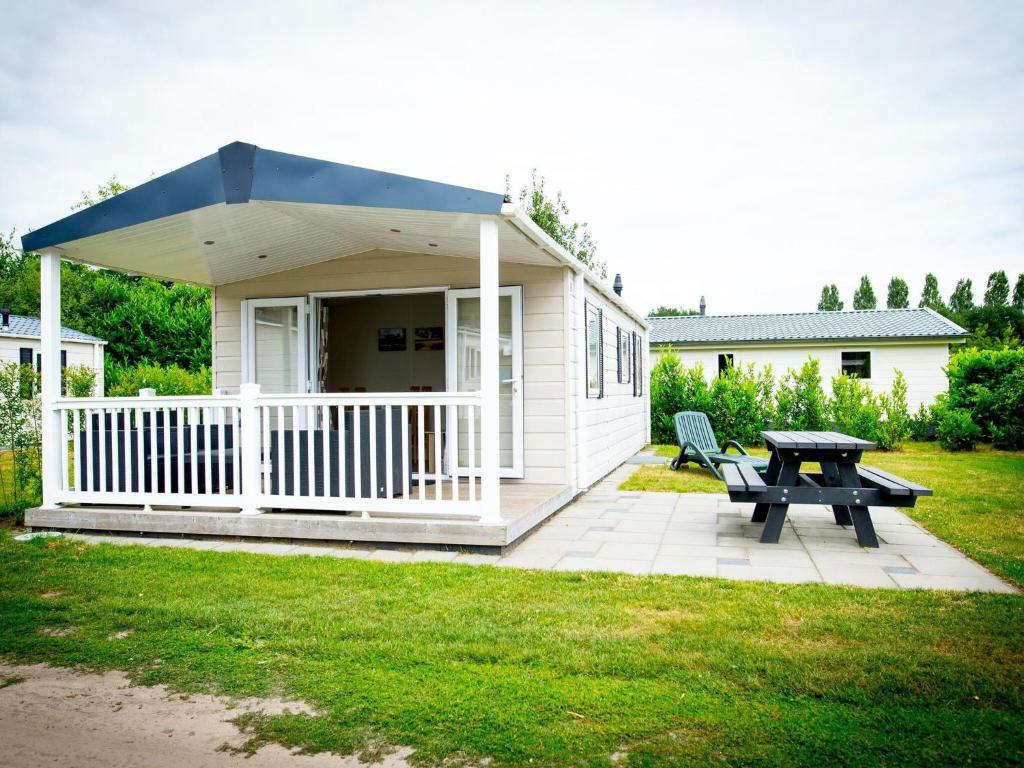 een klein wit huis met een picknicktafel en een bank bij Recreatiepark Duinhoeve 9 in Udenhout