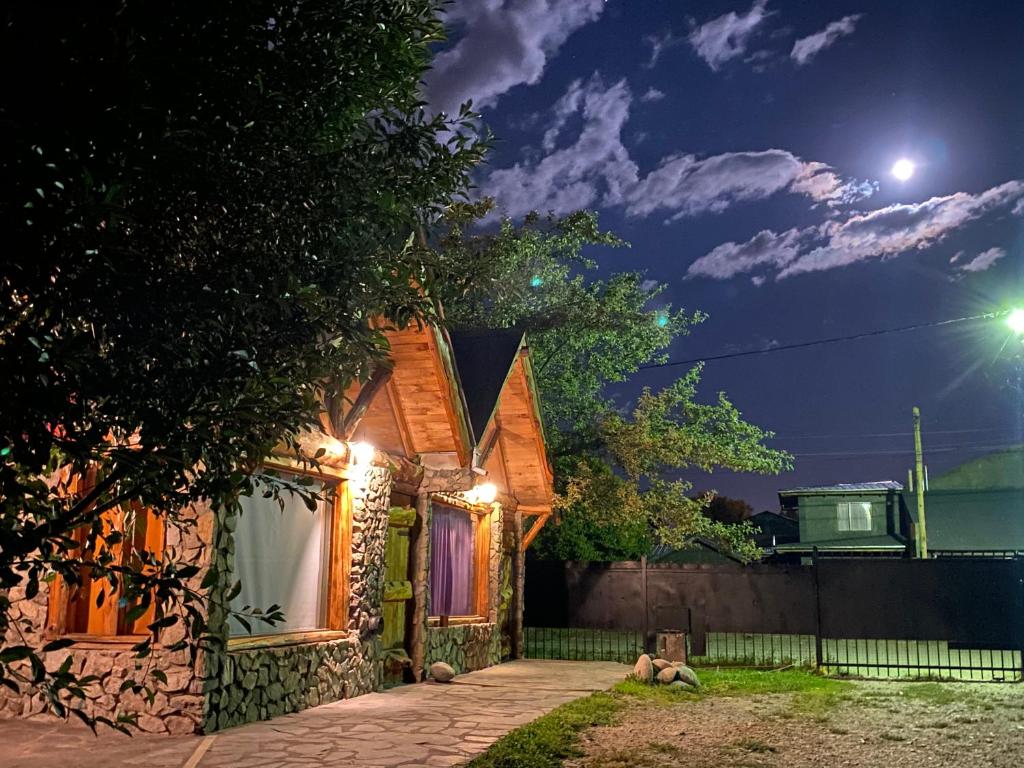 una casa con luces al costado de ella por la noche en HOSTEL PEHUENIA en El Bolsón