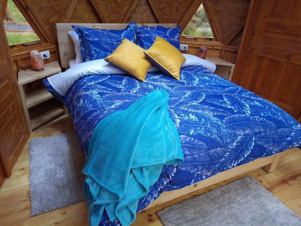 a bed with blue comforter and pillows in a room at Los Nopales Glamping in Sáchica
