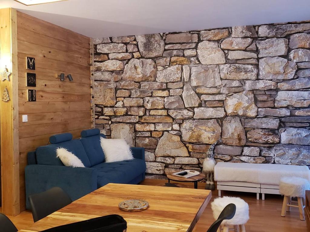 - un salon avec un canapé bleu et un mur en pierre dans l'établissement Charmant T2 au centre de Cauterets avec parking, ascenseur et équipements modernes - FR-1-234-312, à Cauterets