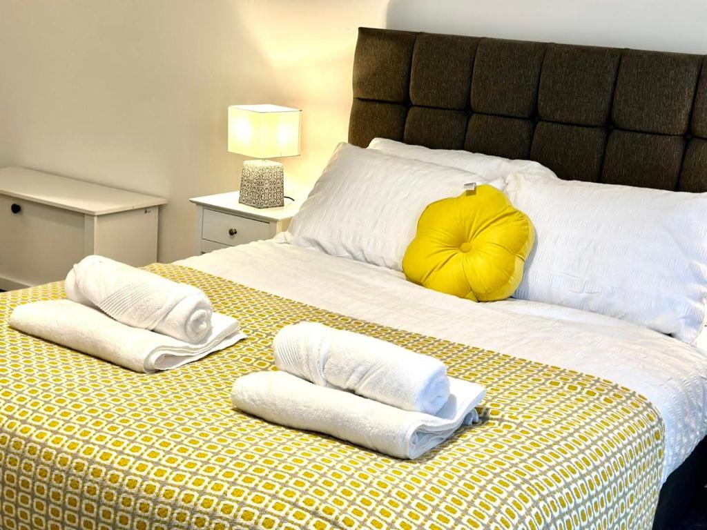 a bed with towels and a yellow pillow on it at Munalux 2 bed in Birmingham
