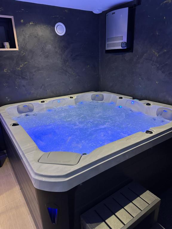 uma banheira de hidromassagem com água azul num quarto em Sweet and Spa em Marly-la-Ville