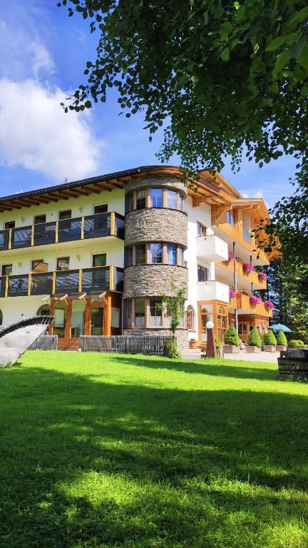 a large building with a grass field in front of it at Guesthouse Rungg in Badia
