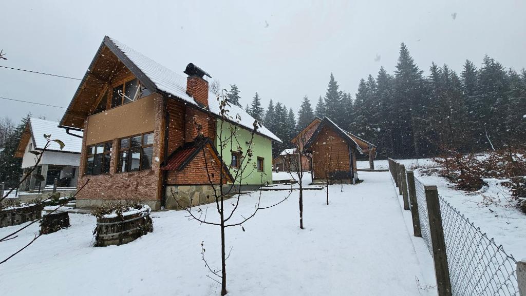 Vikendica Gojković في Skender Vakuf: منزل مغطى بالثلج مع سياج