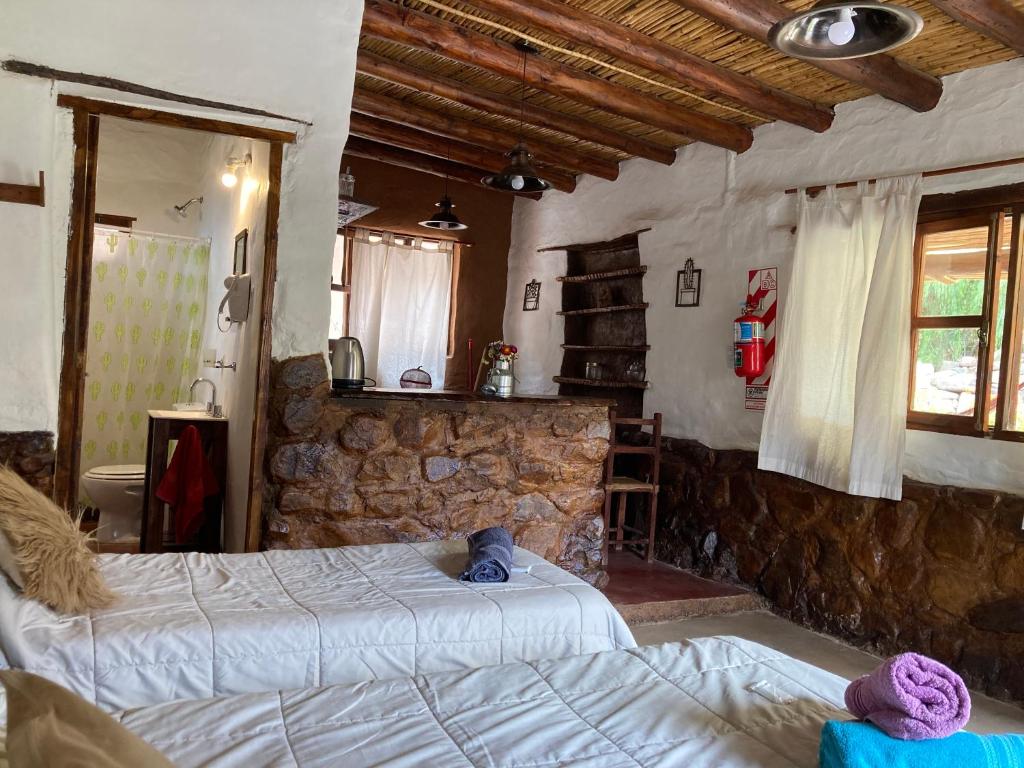 a bedroom with two beds and a stone wall at La Amanecida Tilcara in Tilcara