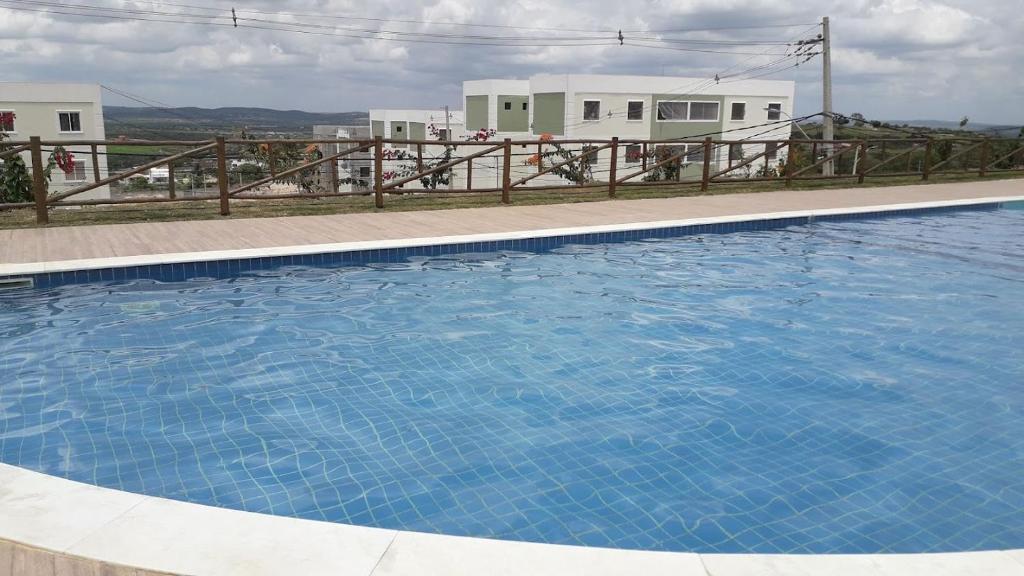 ein großer blauer Pool mit einem Zaun und Häusern in der Unterkunft Apto familiar para Semana Santa in Garanhuns