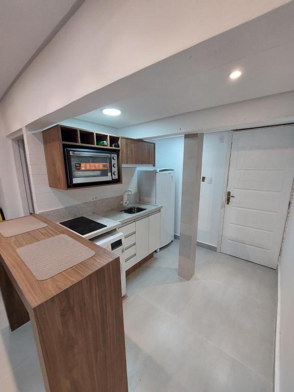 a kitchen with a counter top and a refrigerator at Studio reformado - sem garagem de auto in São Vicente