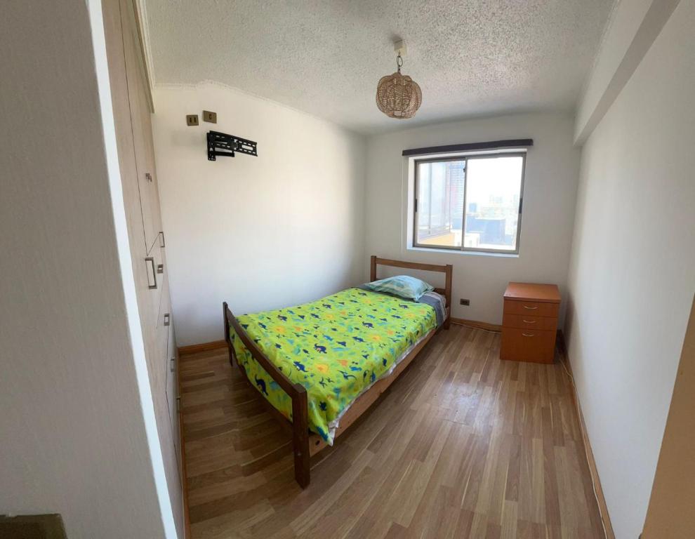 een kleine slaapkamer met een bed en een raam bij Reina Isidora in Iquique