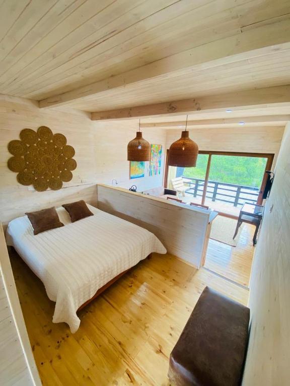1 dormitorio con 1 cama blanca en una habitación de madera en Forest house Cabaña para 2, en Pichilemu