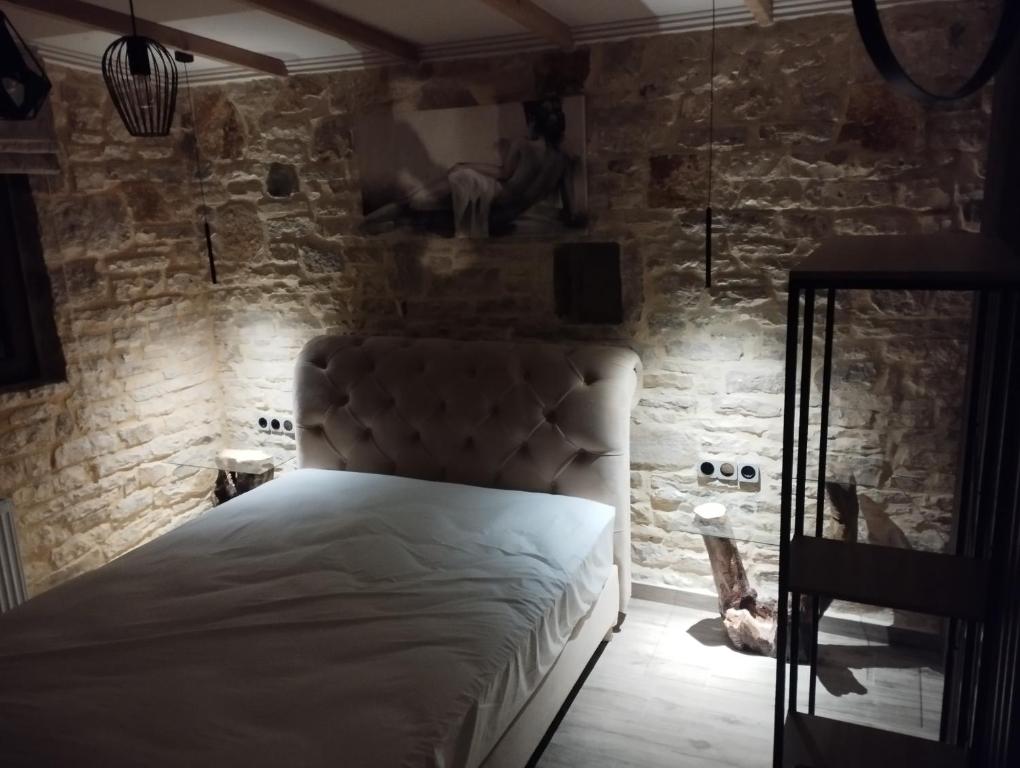a bedroom with a bed in a stone wall at Ekali stone house in Kaléntzion