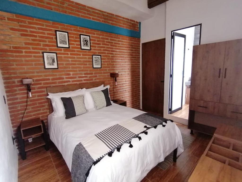 1 dormitorio con 1 cama grande y pared de ladrillo en Suites del Barrio, en San Cristóbal de Las Casas