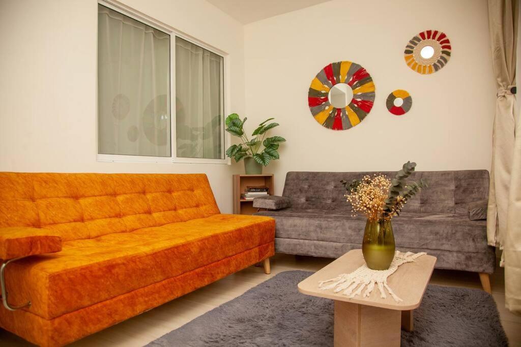 a living room with an orange couch and a table at Acogedor apartamento moderno para 6 personas in Cali