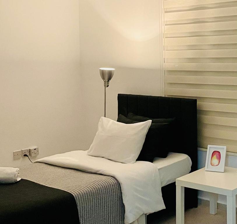 a bedroom with a bed with white sheets and a lamp at Nicocreon Guest House in Famagusta