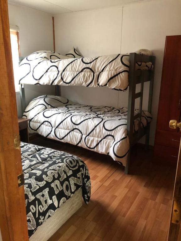 two bunk beds in a room with a wooden floor at Cabañas andino in Punta Arenas