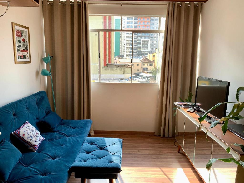 a living room with a blue couch and a window at Apartamento Teatro Conforto no Centro in Curitiba