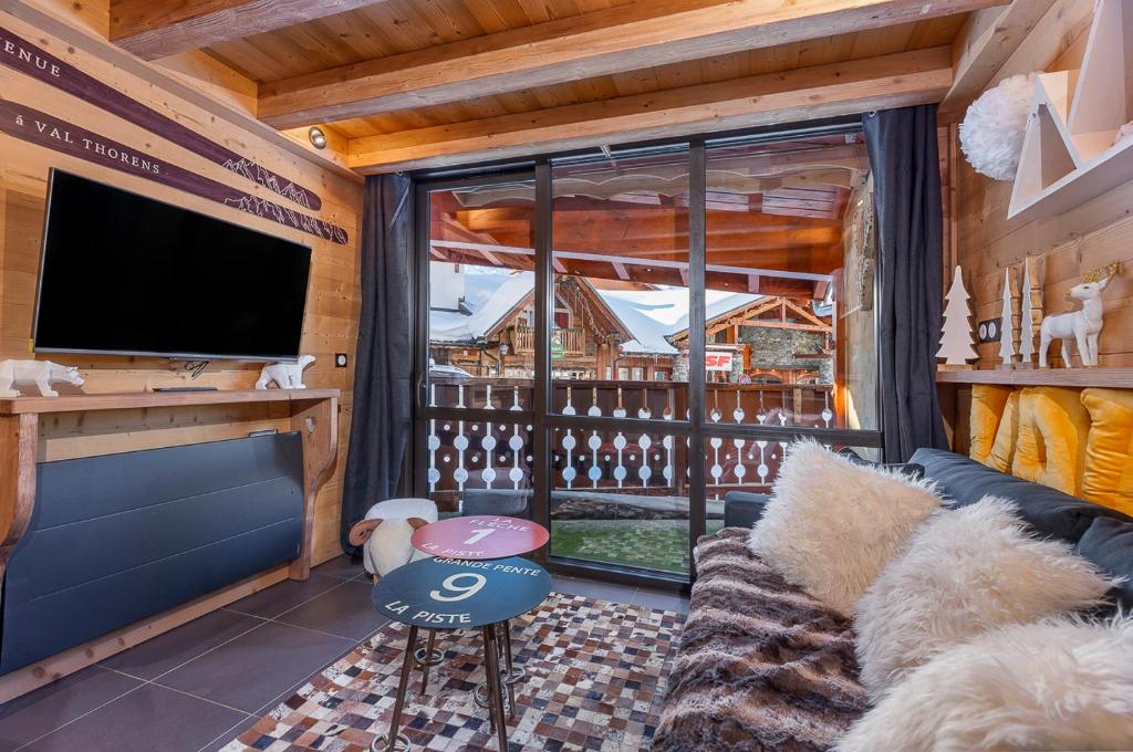 a living room with a couch and a large window at Val Thorens - Cosy Duplex Pied des pistes Silveralp 003 in Val Thorens