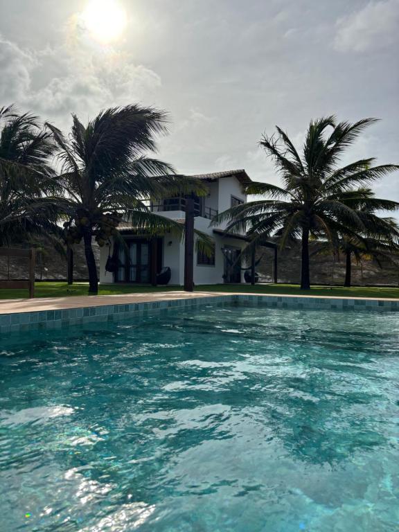 a swimming pool in front of a house with palm trees at Pousada Villa Sagi in Baía Formosa