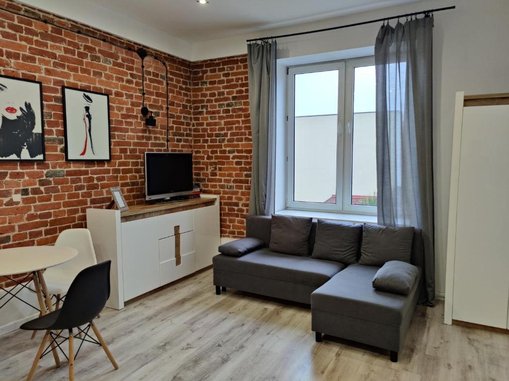 a living room with a couch and a brick wall at Konopnickiej 9 Apartament Loft dostęp na kod in Pabianice