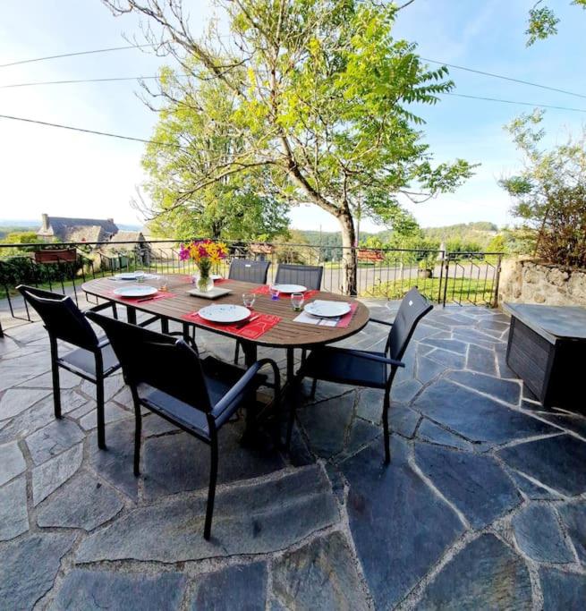 une table et des chaises en bois sur une terrasse en pierre dans l'établissement Le Casimir, Maison de campagne à Estaing, à Estaing